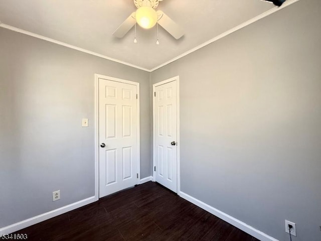 spare room featuring dark wood-style flooring, crown molding, baseboards, and ceiling fan