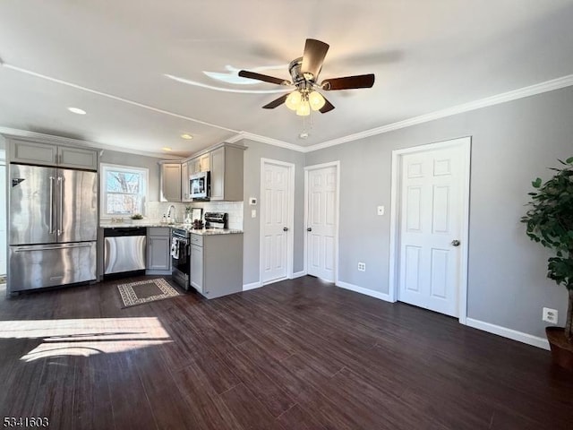 kitchen with gray cabinetry, dark wood-type flooring, baseboards, appliances with stainless steel finishes, and decorative backsplash