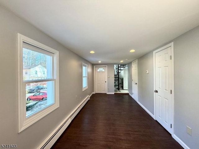 hall featuring dark wood-type flooring, a baseboard radiator, stairway, and baseboards