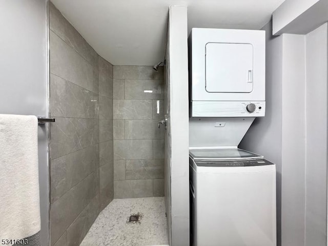 bathroom with stacked washer / drying machine and a tile shower