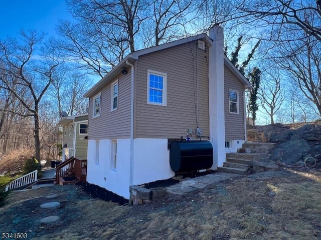 view of property exterior featuring heating fuel and a chimney