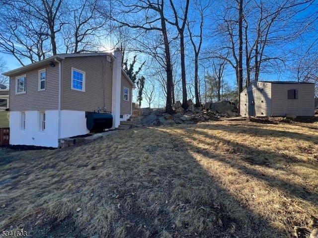 view of side of home with an outbuilding, a storage shed, a chimney, and heating fuel