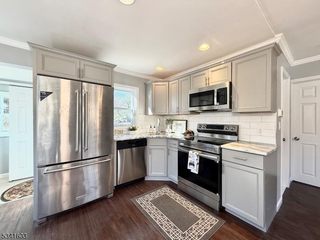 kitchen featuring gray cabinetry, appliances with stainless steel finishes, tasteful backsplash, dark wood finished floors, and crown molding