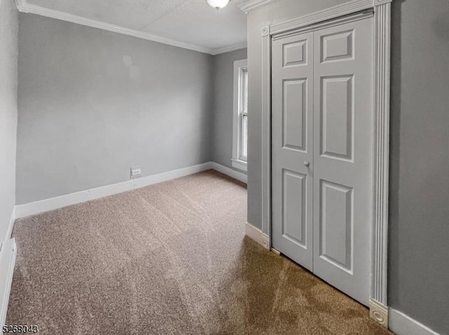 unfurnished bedroom with baseboards, a closet, ornamental molding, and carpet flooring