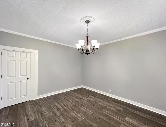 spare room featuring crown molding, dark wood finished floors, baseboards, and an inviting chandelier