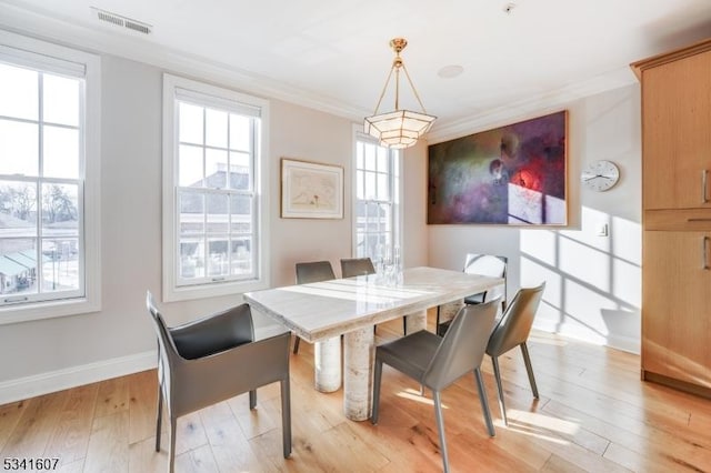 dining area with ornamental molding, visible vents, light wood-style flooring, and baseboards