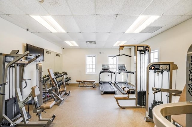 workout area with a paneled ceiling and baseboards