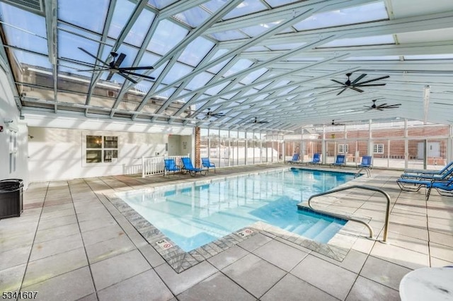 pool with ceiling fan, glass enclosure, and a patio area