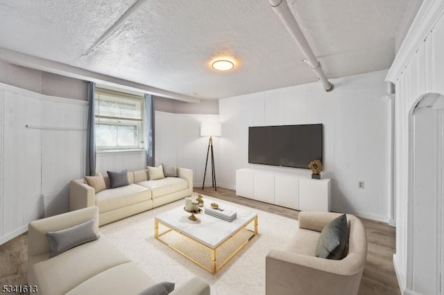 living area with a textured ceiling, wood finished floors, and baseboards