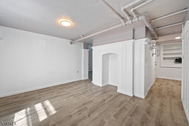 finished basement featuring a textured ceiling and wood finished floors