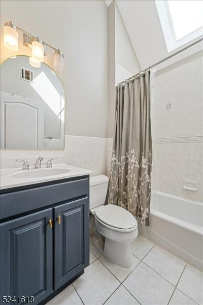 full bathroom with tile walls, visible vents, toilet, vanity, and tile patterned floors