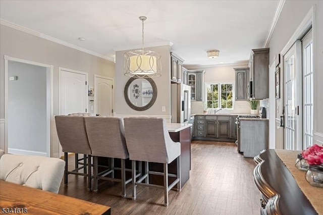 dining space with dark wood-style floors, ornamental molding, and a notable chandelier