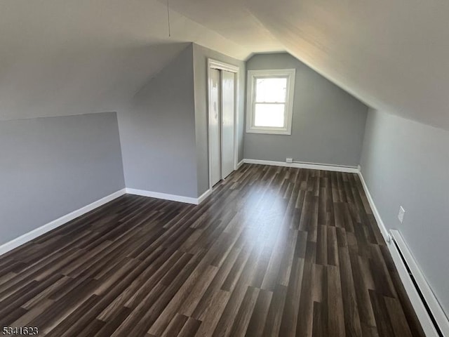 additional living space featuring dark wood-style floors, baseboard heating, lofted ceiling, and baseboards