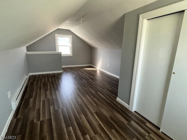 additional living space featuring vaulted ceiling, dark wood-style floors, baseboards, and a baseboard radiator