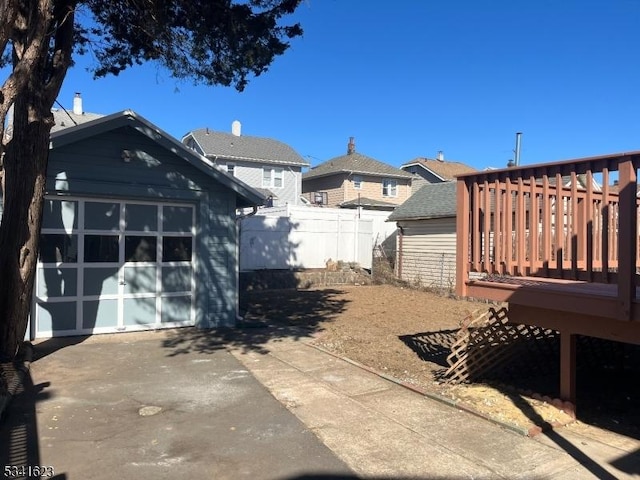 view of yard with a garage, a deck, an outdoor structure, and fence