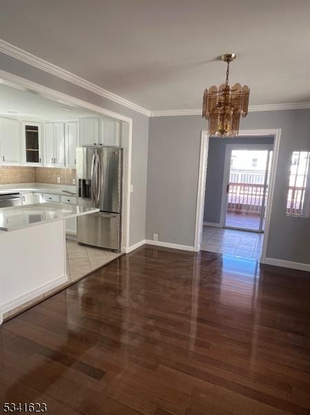 kitchen with backsplash, crown molding, light countertops, an inviting chandelier, and stainless steel appliances