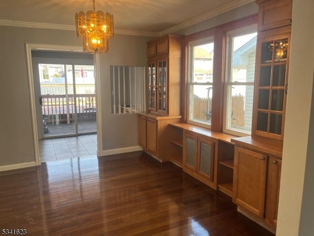 unfurnished dining area featuring baseboards, dark wood-type flooring, a notable chandelier, and ornamental molding