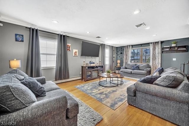 living area with a baseboard radiator, crown molding, visible vents, and wood finished floors