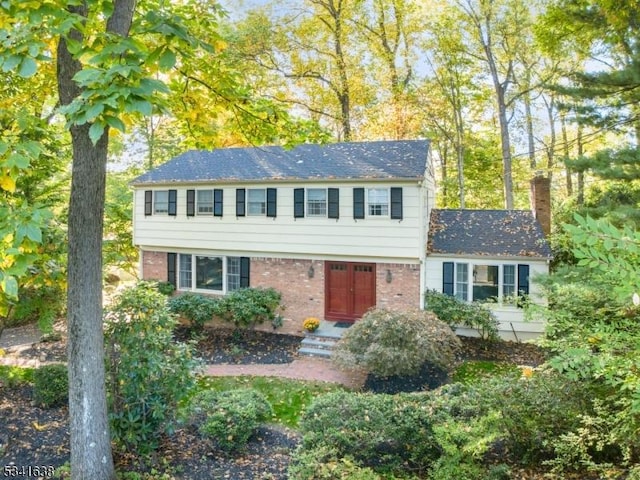 colonial inspired home featuring brick siding and a chimney