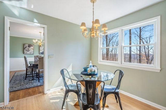 dining area with a chandelier, a healthy amount of sunlight, and wood finished floors