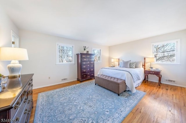 bedroom with light wood finished floors, visible vents, and baseboards