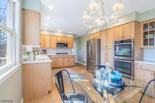 kitchen with appliances with stainless steel finishes, backsplash, a wealth of natural light, and light brown cabinetry