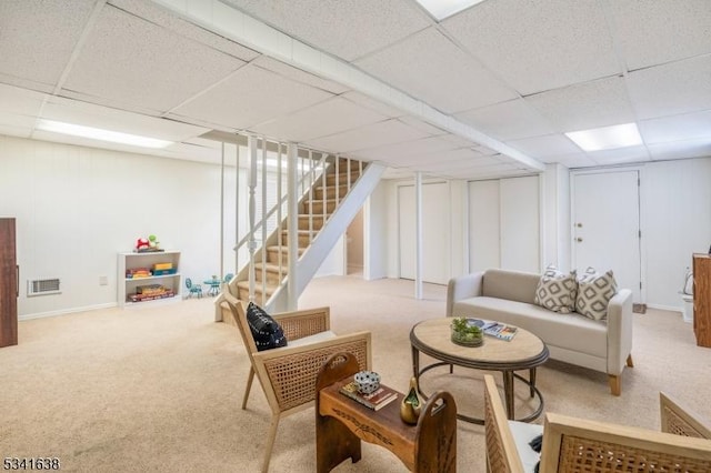 living area featuring carpet floors, visible vents, stairway, and a drop ceiling