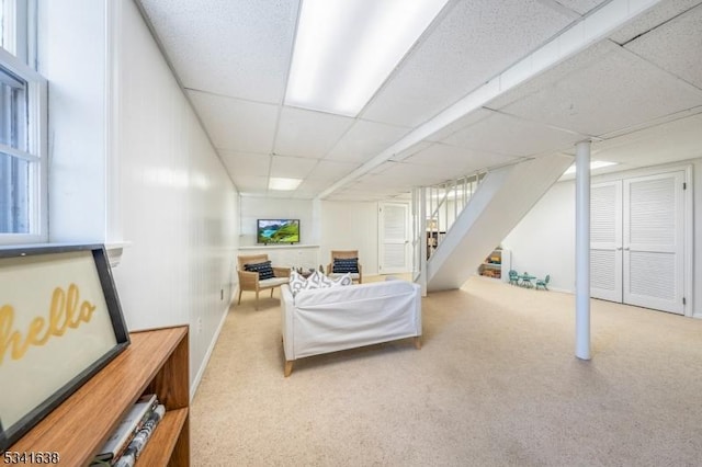 living room with carpet flooring, stairway, and a drop ceiling