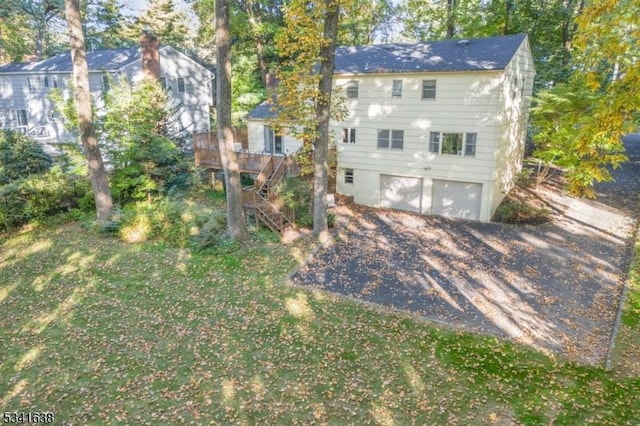 view of front of house with stairs, aphalt driveway, a front lawn, and a garage