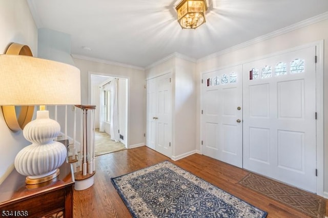 foyer entrance with ornamental molding, wood finished floors, and baseboards