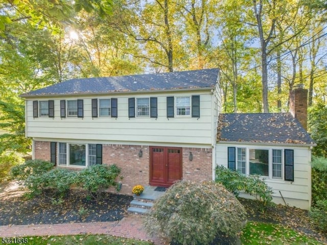 colonial home featuring brick siding and a chimney