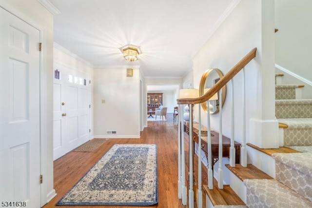 foyer entrance featuring ornamental molding and wood finished floors