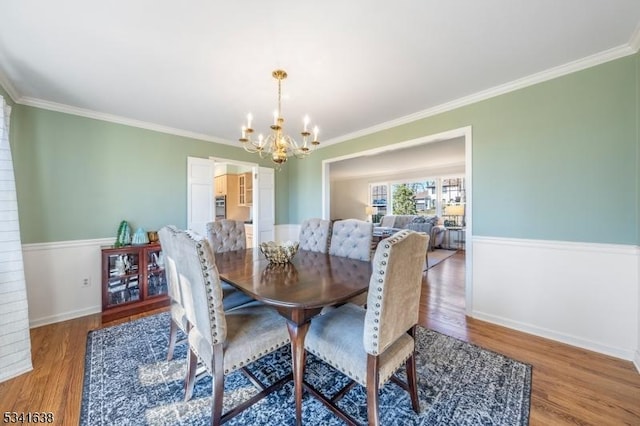 dining room with a chandelier, ornamental molding, wood finished floors, and baseboards