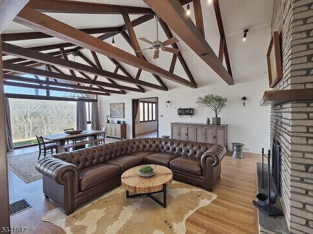 living room featuring a fireplace, visible vents, a ceiling fan, high vaulted ceiling, and light wood-type flooring