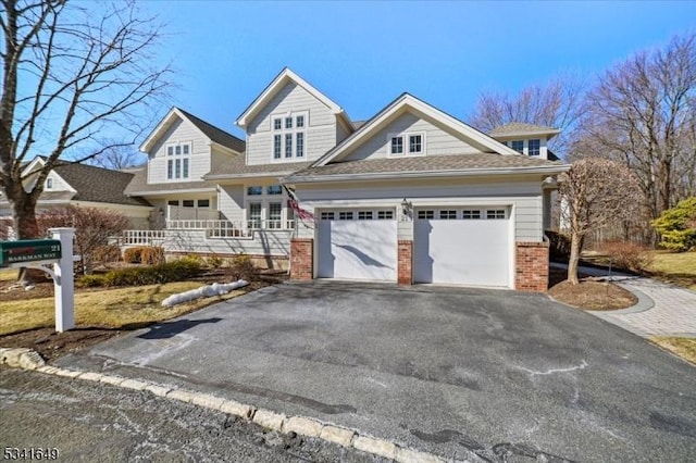 view of front of home featuring aphalt driveway, brick siding, and a garage