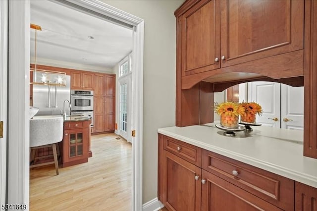 kitchen with double oven, brown cabinets, light countertops, and light wood-style flooring