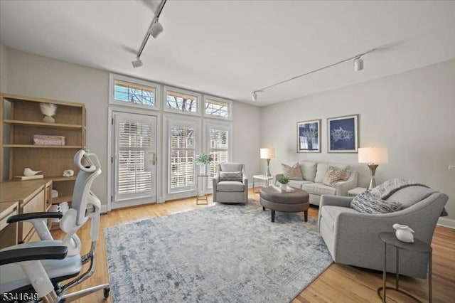 living area with baseboards, wood finished floors, and track lighting