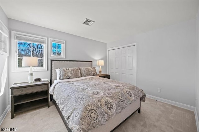 bedroom with baseboards, a closet, visible vents, and light colored carpet