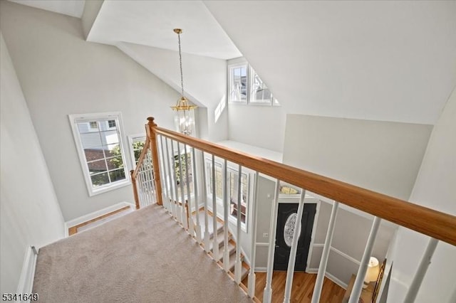 hallway featuring vaulted ceiling, a notable chandelier, and an upstairs landing