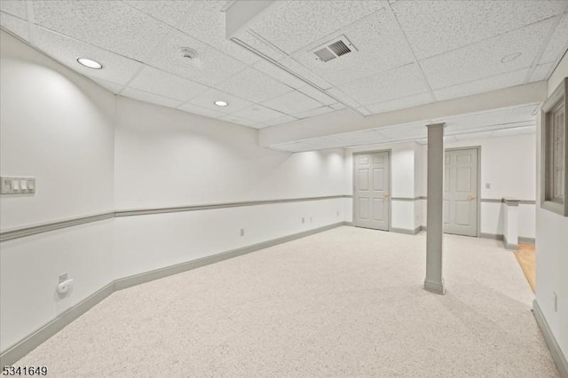 finished below grade area featuring light carpet, a paneled ceiling, visible vents, and baseboards