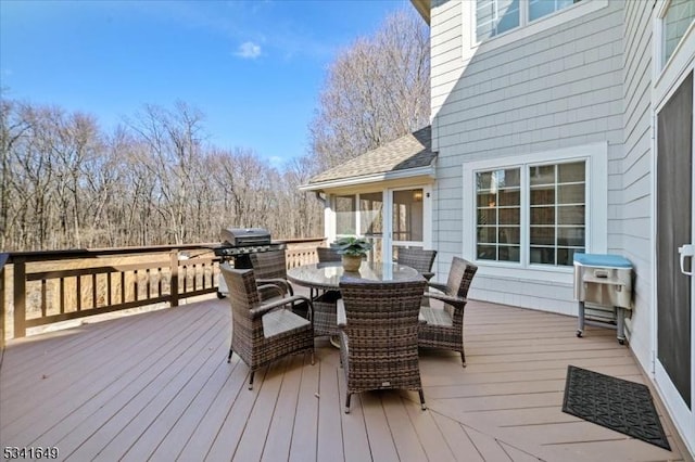 wooden terrace featuring outdoor dining area and a grill