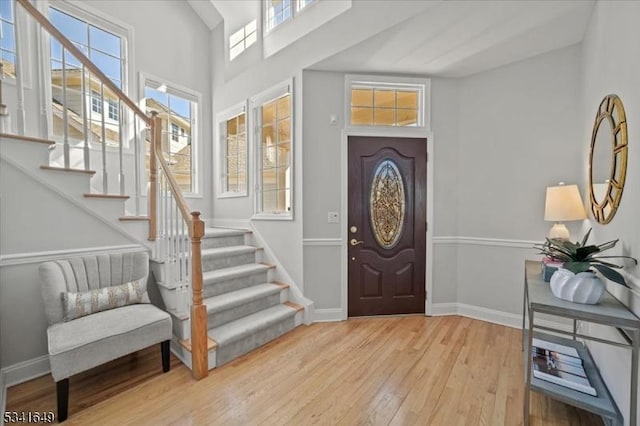 foyer entrance with stairway, light wood-style flooring, and baseboards