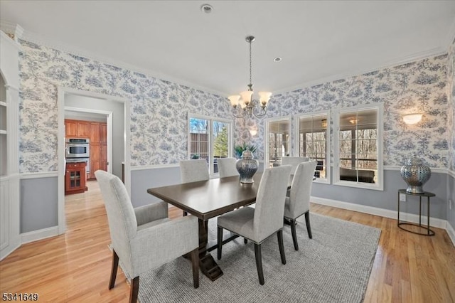 dining area featuring a chandelier, wainscoting, light wood-style flooring, and wallpapered walls