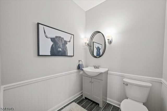 half bath featuring toilet, wainscoting, and vanity