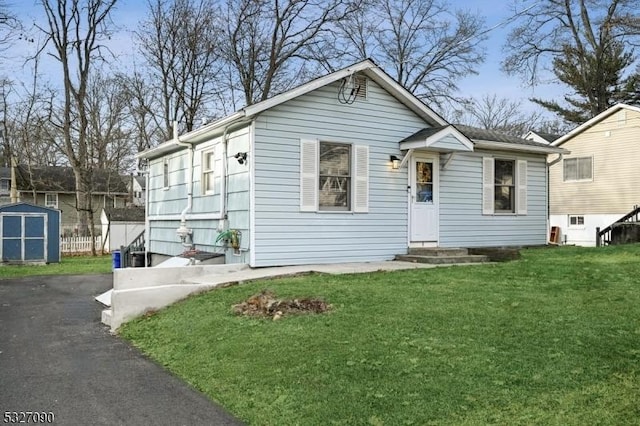 view of front of home with an outdoor structure, fence, a front lawn, and a shed