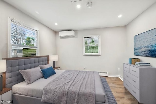 bedroom with recessed lighting, light wood-style floors, a baseboard heating unit, an AC wall unit, and baseboards