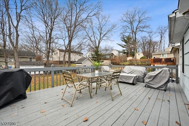 wooden terrace featuring outdoor dining space, grilling area, and a residential view