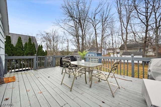 wooden deck with an outbuilding, outdoor dining area, and a shed