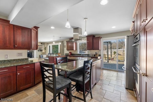 kitchen featuring reddish brown cabinets, island exhaust hood, and stone tile flooring