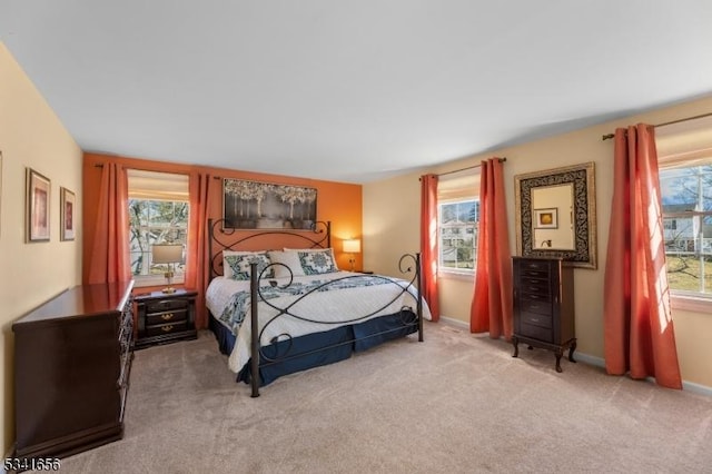 carpeted bedroom featuring multiple windows and baseboards